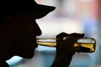 Мужчина пьет пиво из бутылки