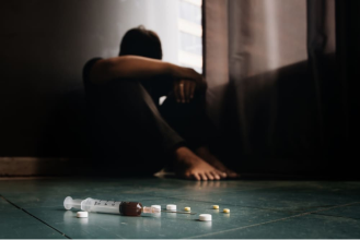 Шприц и таблетки лежат на фоне мужчины